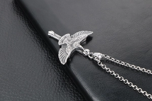 Gros plan d'un pendentif aigle vintage avec plumes argentées sur surface en cuir noir