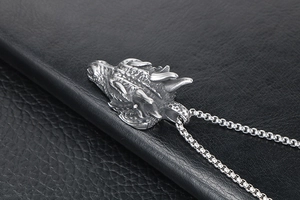 Détail macro du pendentif tête de dragon en argent avec chaîne sur fond de cuir noir