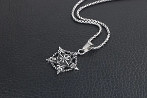 Macro shot of vintage titanium steel compass pendant with detailed relief on black leather