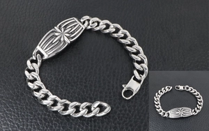 Close-up of a stainless steel Cuban chain bracelet with a vintage starburst pattern plate