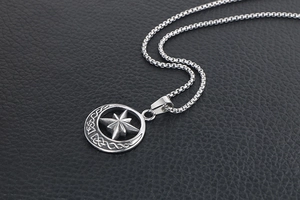 Macro shot of silver vintage compass pendant with Celtic patterns on black leather
