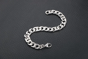 Gros plan d'un bracelet gourmette argenté poli avec inserts ronds sur fond de cuir