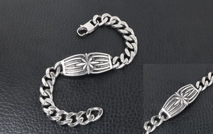 Detailed macro view of silver Cuban link bracelet with engraved starburst metal plaque