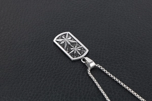 Detailed close-up of retro titanium steel dog tag pendant with engraved stars on black leather