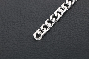 Vue macro d'un bracelet gourmette en acier inoxydable poli argent sur cuir noir