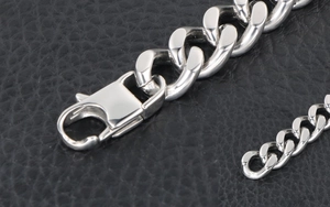 Macro detail of silver Cuban link chain with secure lobster clasp on black leather