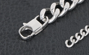 Macro detail of polished stainless steel curb chain bracelet with large lobster clasp