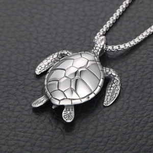 Realistic turtle pendant necklace in polished titanium steel on black leather background