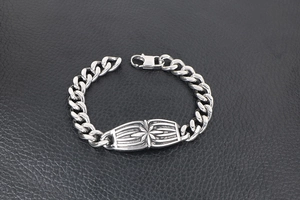 Macro detail of men's stainless steel Cuban chain bracelet with star motif oval charm