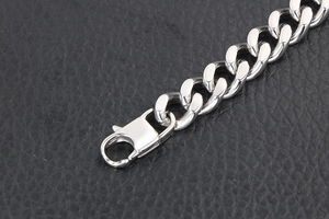 Vue macro d'un bracelet gourmette en acier argenté avec fermoir mousqueton sur cuir