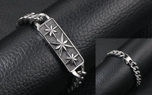 Detail view of Cuban chain bracelet with engraved star pattern and textured metal plate