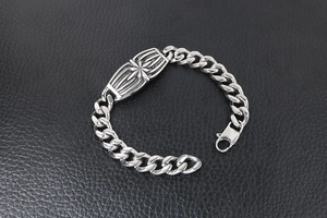 Detail of chunky stainless steel Cuban chain bracelet with star-embossed centerpiece plaque