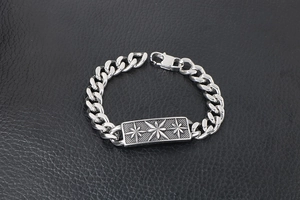 Detailed view of silver Cuban chain bracelet with engraved star pattern on a leather background
