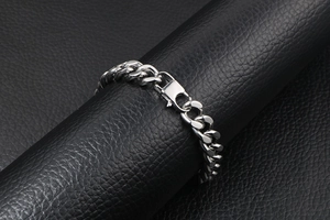 Macro shot of silver stainless steel Cuban link bracelet with fold-over clasp detail