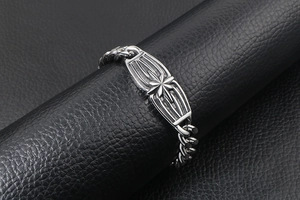 Detail of silver cuban chain bracelet featuring an embossed octagonal star on the plaque