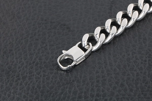 Detail shot of silver Cuban link chain bracelet with a precision lobster clasp on leather