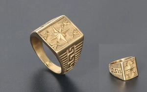 Macro detail of men's matte gold signet ring with star compass and Greek key pattern