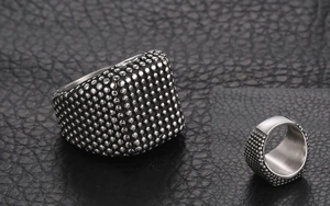 Gros plan d'une bague punk en acier titane pour homme avec texture cloutée et dessus plat