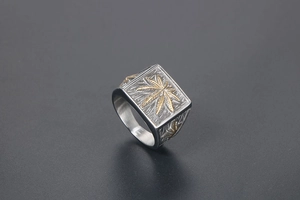 Detail of vintage square signet ring with gold leaf relief on brushed silver metal