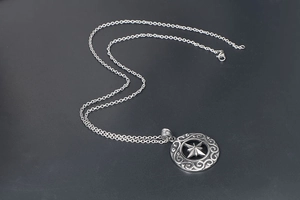 Dettaglio di una collana vintage in argento con pendente a stella ottagonale inciso