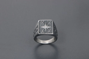 Detailed close-up of a vintage steel signet ring with an engraved eight-pointed star design