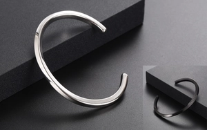 Macro shot of minimalist twisted open bangles in silver and black polished finishes
