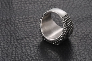 Gros plan de la bague punk en acier titane pour homme avec texture rivet et haut poli