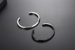 Macro view of minimalist twisted open cuff bracelets in silver and black metal