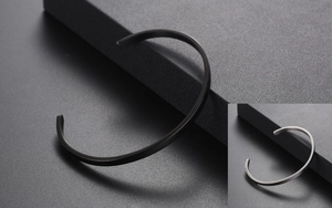Detail view of minimalist C-shape bracelets in matte black and brushed silver finishes