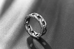 Macro detail of silver titanium steel curb link ring showing heavy industrial texture