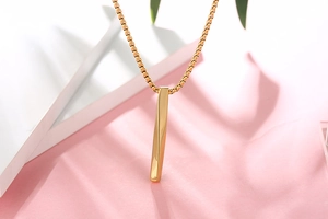 Detailed shot of golden twisted bar pendant with box chain on a minimalist background