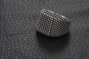 Vue macro d'une bague chevalière pour homme en acier avec texture perlée sur cuir noir