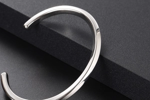 Close-up of high-polished silver twisted open bangle showing glossy metallic texture