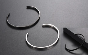 Detailed macro view of minimalist matte finish silver and black C-shaped cuff bracelets