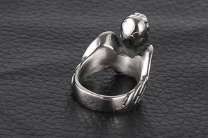 Macro d'une bague en acier titane avec ailes d'ange et détails de gravures gothiques en métal