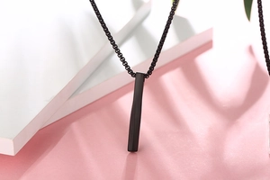 Macro view of matte black square bar pendant on a matching beaded chain necklace