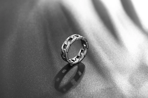 Macro view of polished cuban link chain ring casting a shadow on a silk background