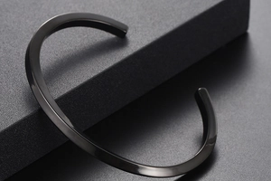 Macro view of polished black C-shaped open bracelet with a minimalist mirror finish