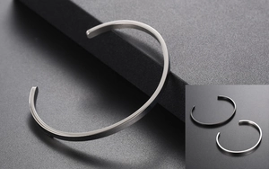Macro detail of minimalist C-shape metal bangles in silver and black finishes