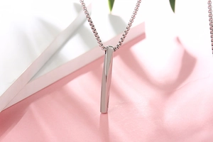 Macro shot of silver twisted square bar pendant on box chain with modern metallic texture