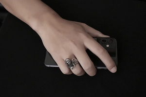 Gros plan sur une bague d'ange en acier titane vintage portée au doigt sur fond sombre