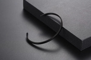 Macro detail of minimalist matte black stainless steel cuff bracelet on rock texture