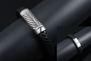 Detail of black braided leather bracelet featuring engraved steel feather clasp closure