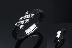 Detail of black braided leather men's bracelet with polished silver clasp and flame relief