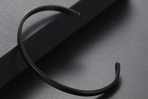 Macro shot of minimalist matte black C-shaped open cuff bracelet in titanium steel