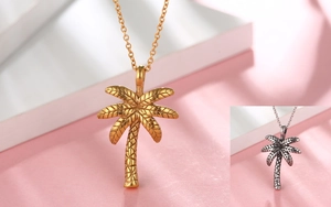 Close-up of two-tone palm tree pendants in gold and aged silver with detailed textures