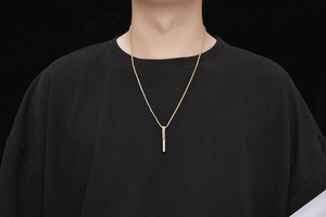 Macro detail of male model wearing a minimalist gold square bar pendant necklace