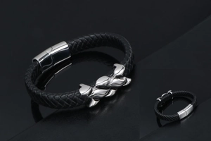 Detail of black braided leather bracelet for men with magnetic clasp and silver metal charm