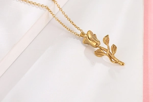 Détail macro du pendentif rose dorée avec pétales texturés et chaîne délicate assortie