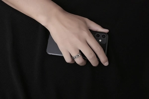 Polished silver cuban link chain ring for men worn on finger holding a black smartphone